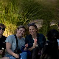 Family posing with dog and ice cream on lawn.